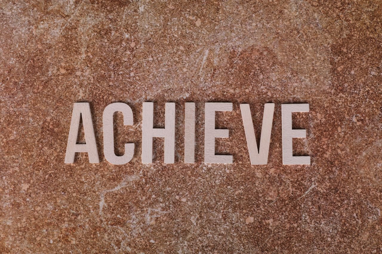 Services Wooden letters spelling 'ACHIEVE' on a textured brown surface, conveying motivation and success.